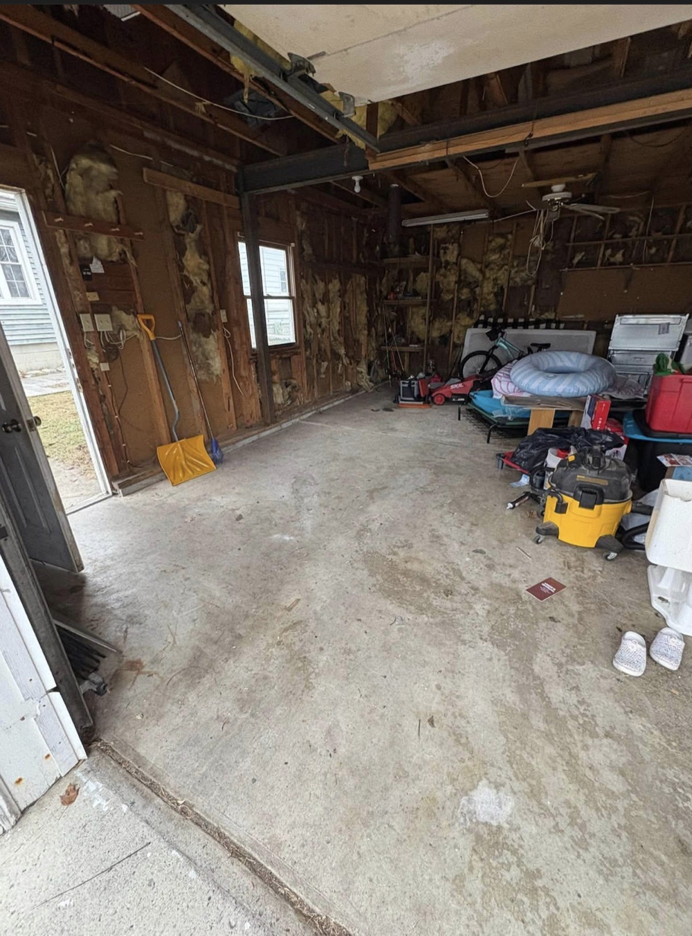 Garage floor opened up after a cleanout, with a smaller group of belongings remaining at the back