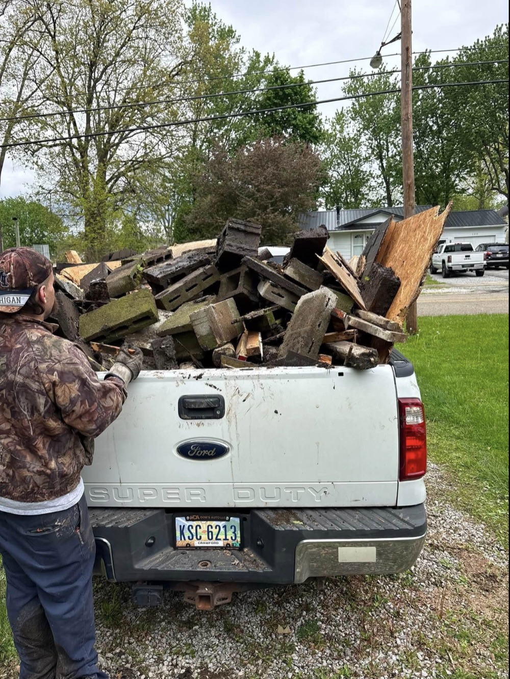 Trey Johnson beside a pickup truck loaded with debris during a cleanup job